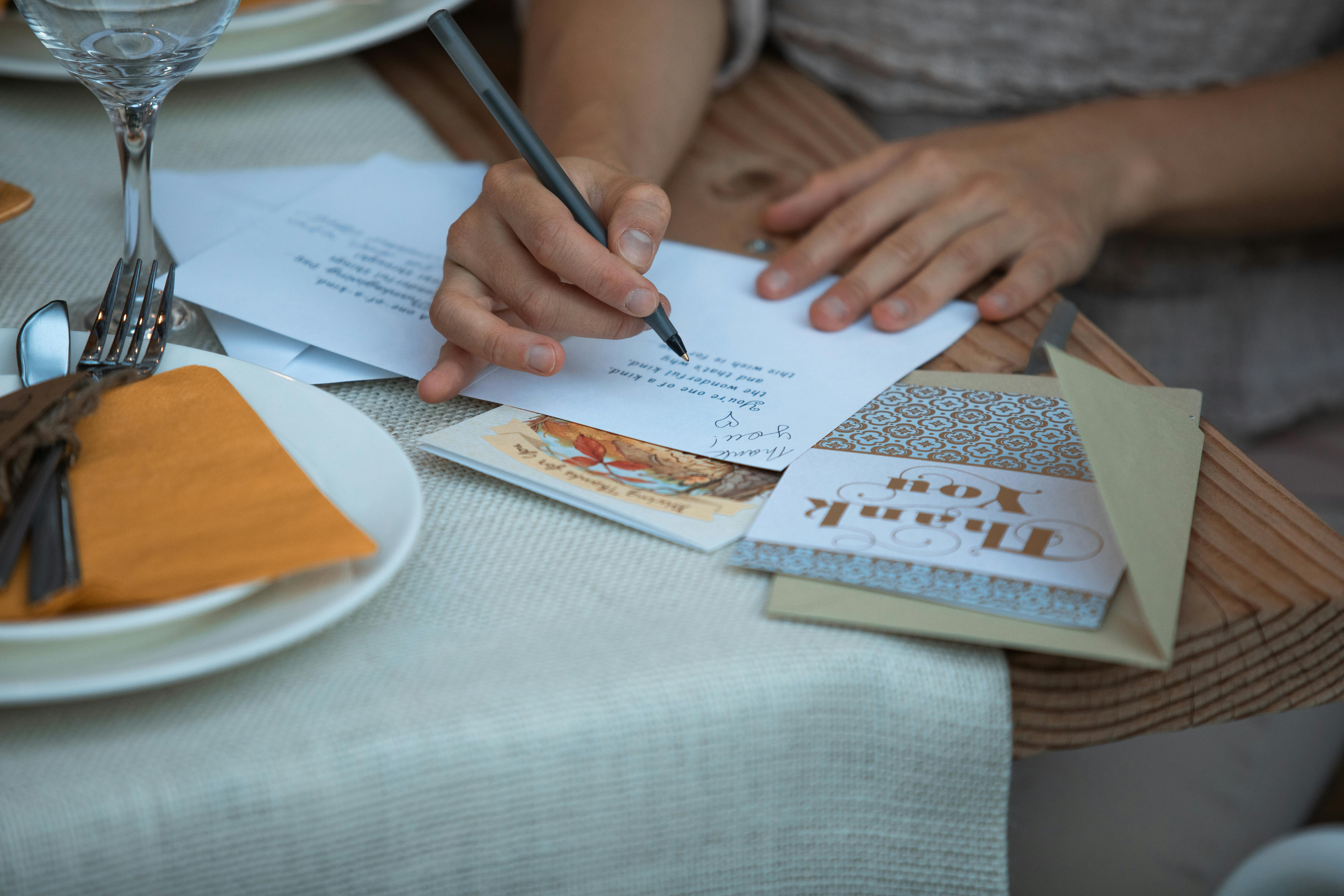person writing a thank you note